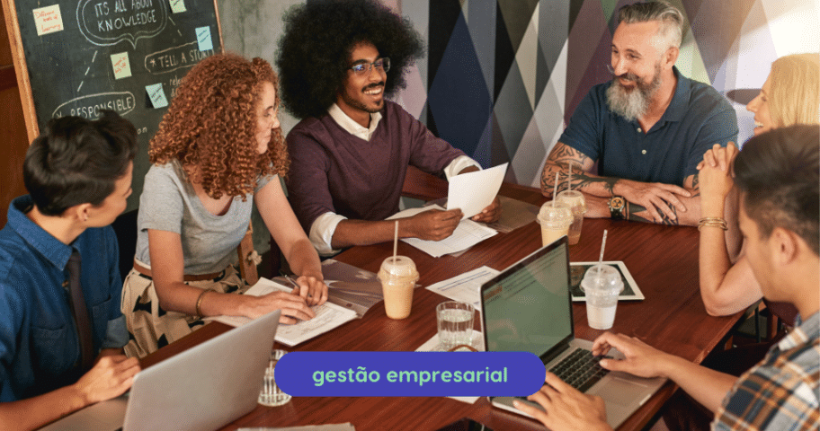 Descrição de Imagem: Grupo de profissionais diversos discutindo estratégias em reunião de startup com foco em gestão empresarial, destacando colaboração e inovação no ambiente corporativo.