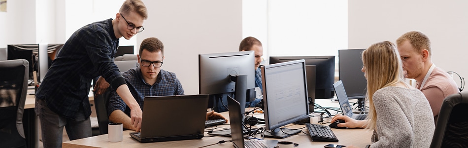Descrição de Imagem: Um grupo de pessoas trabalhando em computadores em um escritório.