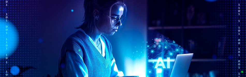 Descrição de Imagem: Uma mulher sentada em frente a um computador com uma luz de fundo azul iluminando seu espaço de trabalho.
