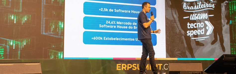 Descrição da imagem: O diretor de mercado da Tecnospeed, Jonathan Santos, está no palco do ERP Summit 2024 ministrando palestra sobre inovação em software.