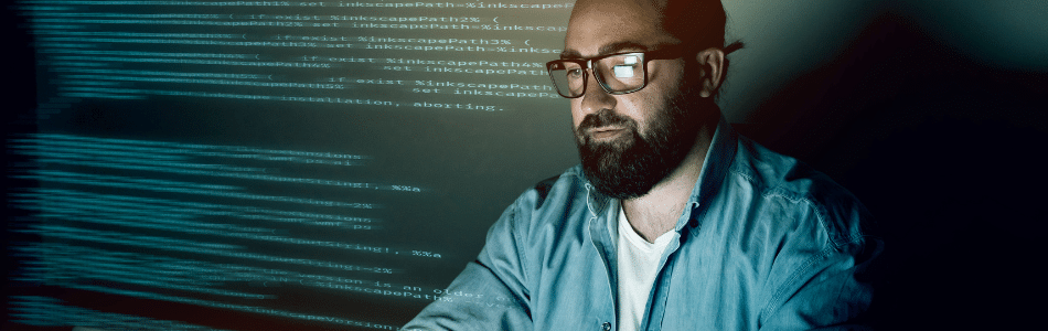Descrição de Imagem: Homem branco de óculos de grau olhando para a tela do computador com códigos de programação em sua volta trabalhando com WebScraping.