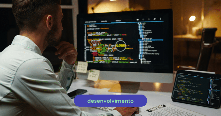 Descrição de Imagem: Um homem está sentado em uma mesa trabalhando em projetos de codificação exibidos em um grande monitor de computador e em um tablet. A tela mostra linhas de código coloridas e há notas adesivas no monitor. A palavra “desenvolvimento” está destacada na parte inferior, ao lado de diversas ferramentas de produtividade para JavaScript.